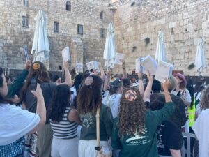 Women praying at the Kotel with Sidurim raised high