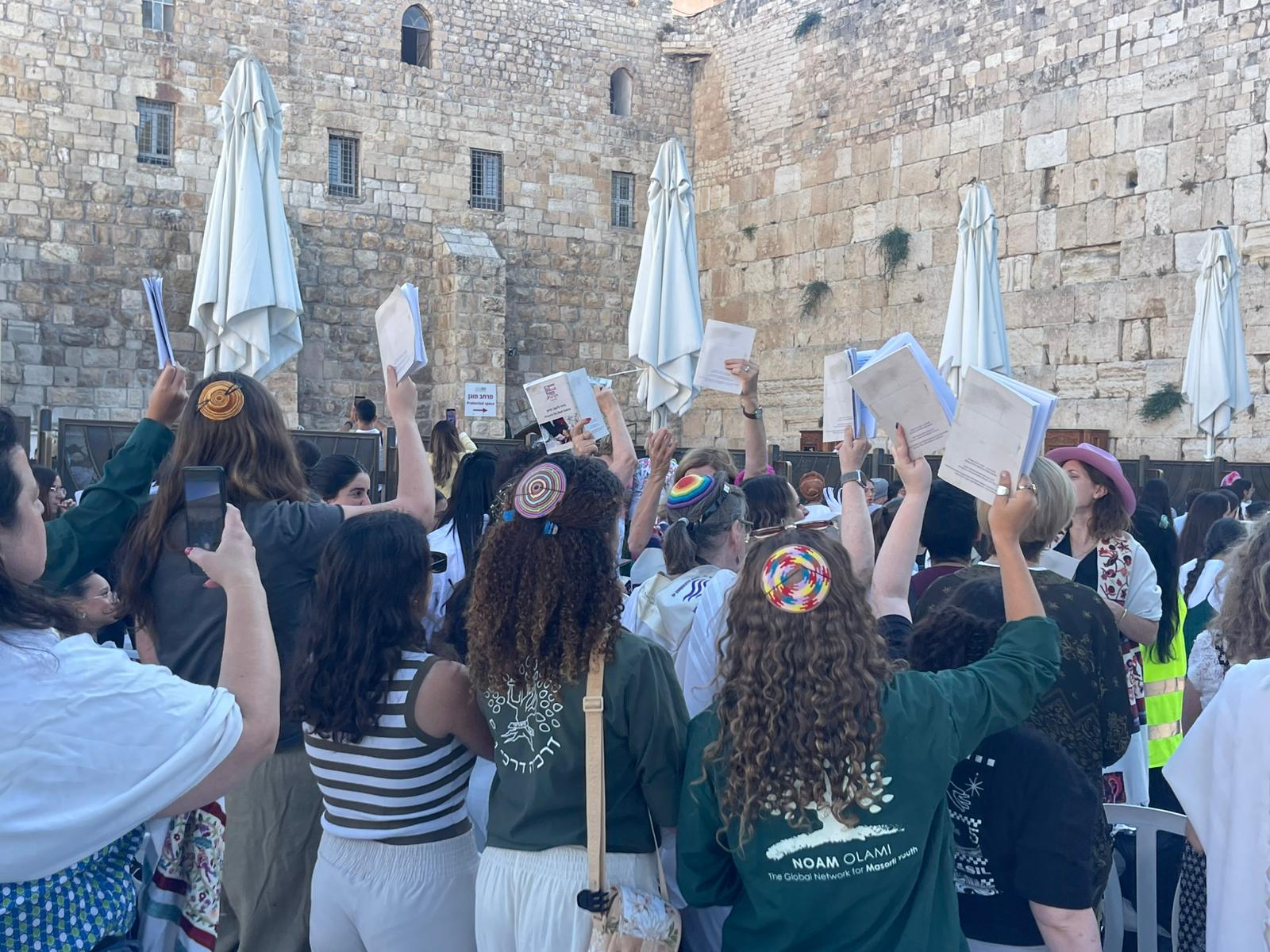 Women praying at the Kotel with Sidurim raised high